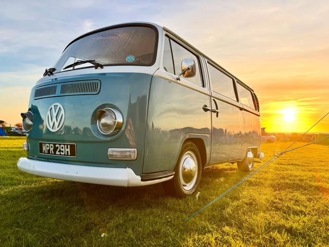 Vintage blue and cream VW camper wedding car photographed at sunset in a Lancashire field